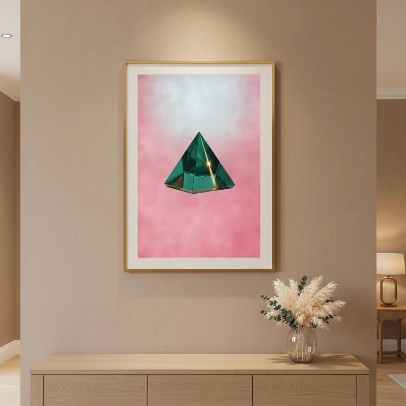 a framed artwork of a green triangular object on a pink background, hanging on a wall above a wooden dresser.