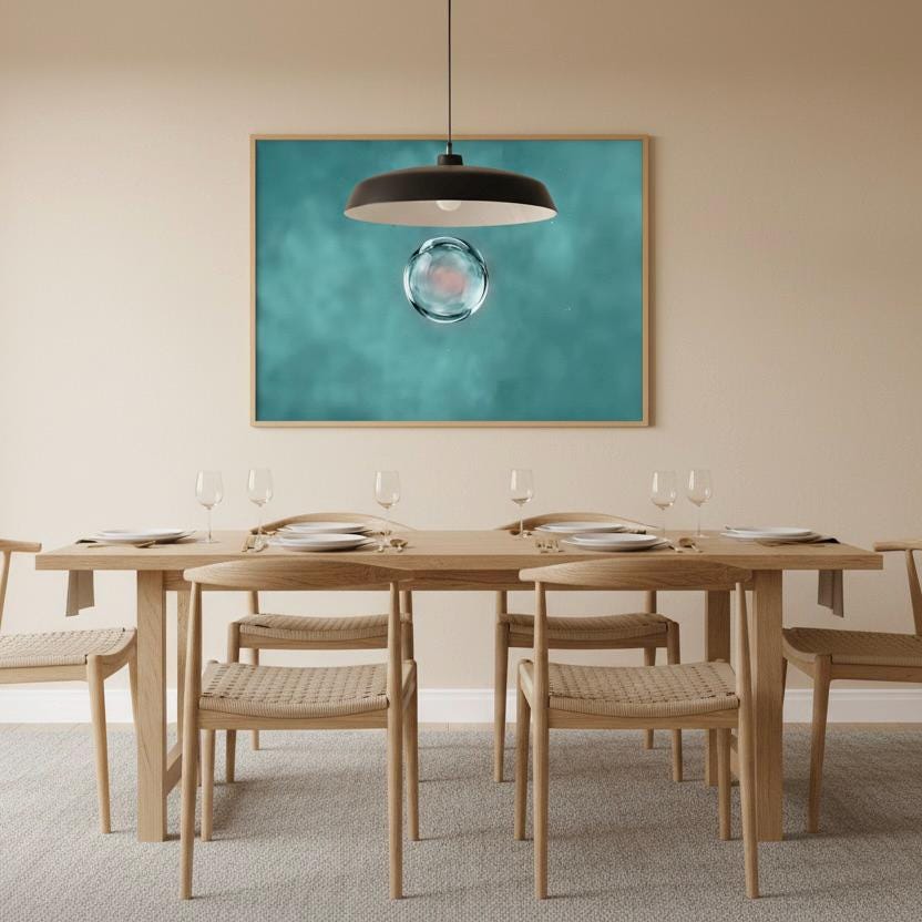 a modern dining room with a wooden table set for four, featuring white plates and wine glasses. Above the table, a framed image of a bubble is displayed on the wall.