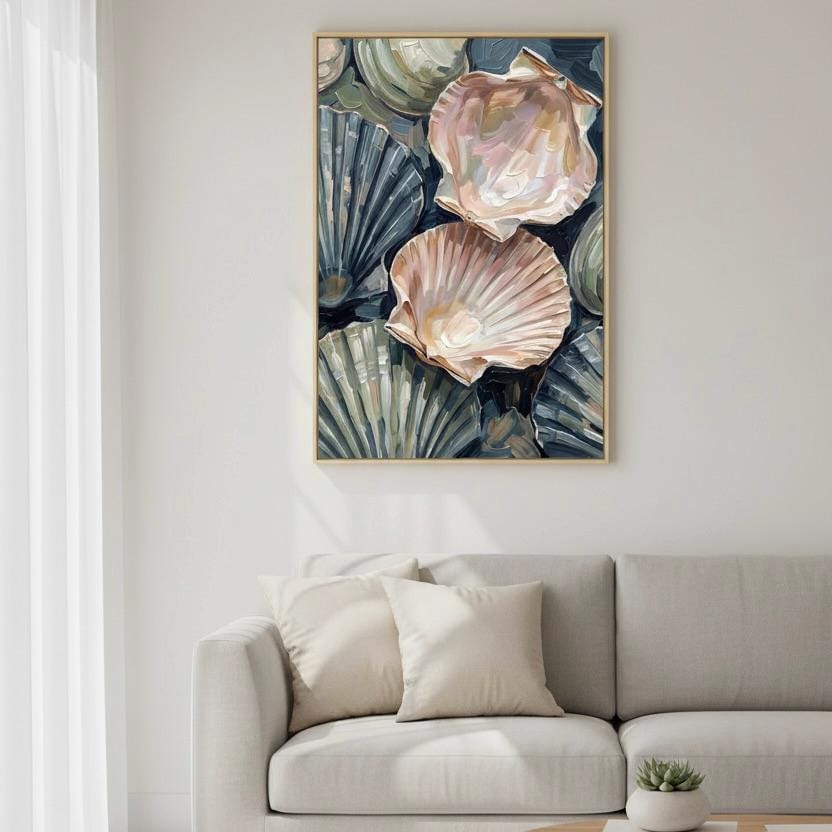a large framed artwork of seashells hanging on a wall above a gray couch with white pillows.