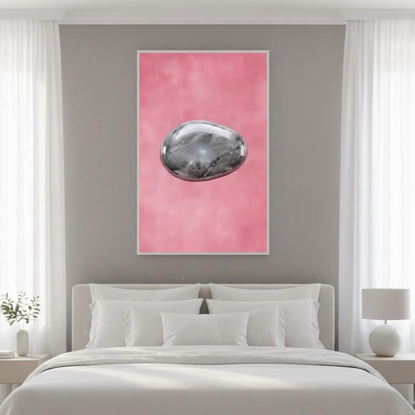 a large bed with white pillows and a white headboard, positioned in front of a pink wall. Above the bed, there is a framed artwork depicting a silver rock or gemstone against a pink background.